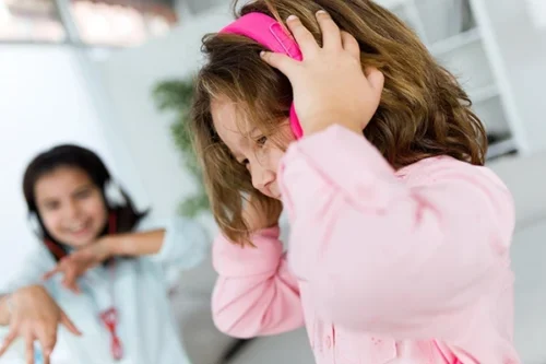 Young girl wearing pink headphones to manage anxiety and sensory overload.