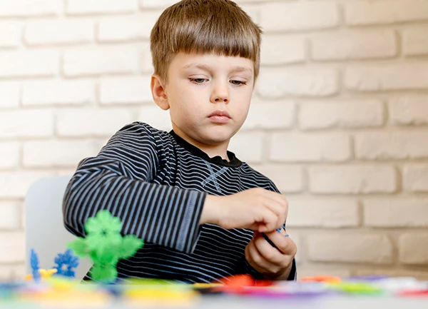 Young boy engaging in focused play with building toys to help calm and manage childhood anxiety.