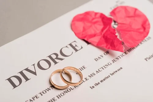 Divorce papers with wedding rings and a torn paper heart, representing family transitions.