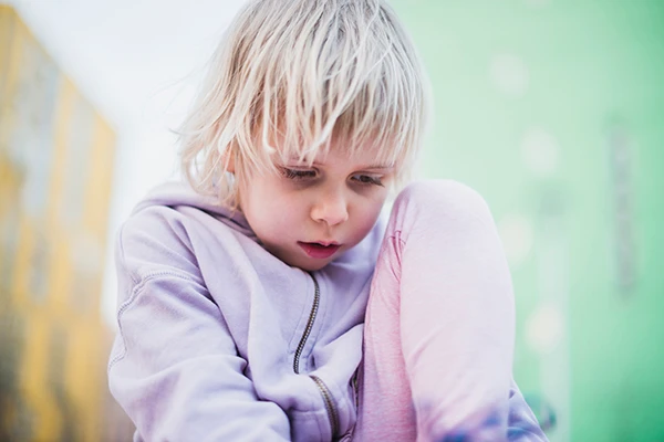 Young child looking down with an anxious expression, illustrating signs of anxiety in children.