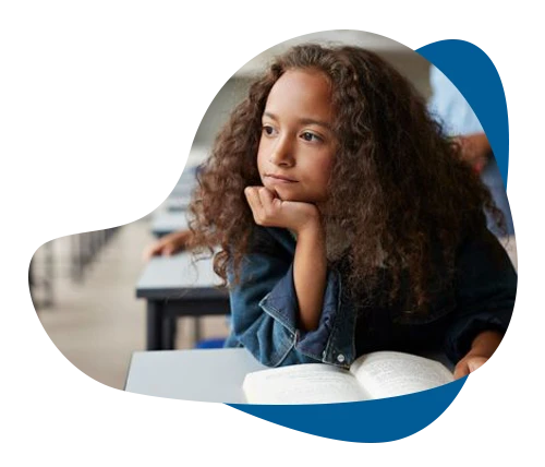 Young girl looking distracted at a classroom desk with an open book, illustrating childhood ADHD and focus challenges.