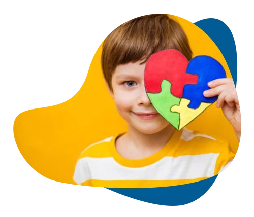 Smiling boy holding a colorful autism spectrum puzzle heart over his eye