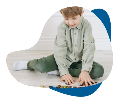 Young boy meticulously organizing small colored stones on the floor during child OCD therapy.