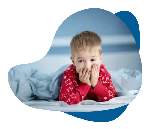 Young boy in pajamas sitting awake in bed, representing sleep therapy for children in Richmond Hill.