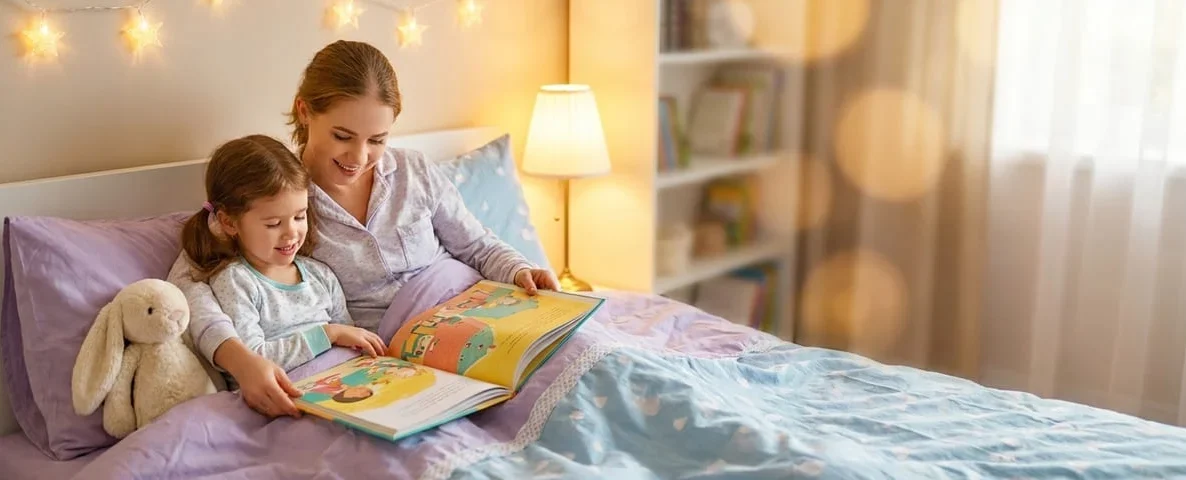 Mother and daughter reading a picture book together at bedtime under star lights, Solutions for Sleeping Disorders course by Alpha Child Therapy