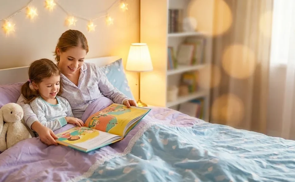 Mother and daughter reading a picture book together at bedtime under star lights, Solutions for Sleeping Disorders course by Alpha Child Therapy