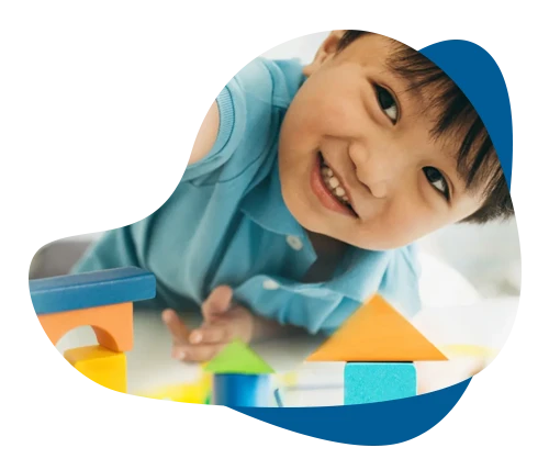 Smiling boy playing with colorful building blocks during a pediatric therapy assessment.
