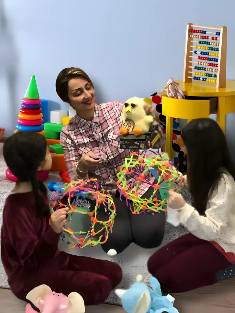 Child therapist engaging with two young girls using colorful toys during a play therapy session.