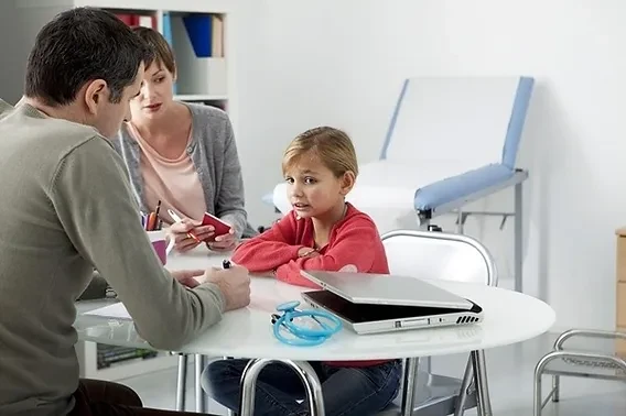 Child therapist consulting with a young girl and her mother during a pediatric therapy session.