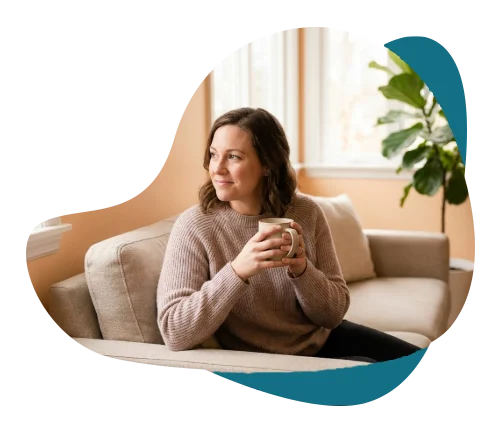Calm mother holding a mug on a sofa, representing adult therapy and counselling for parents in Richmond Hill.