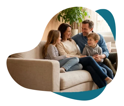 Parents and two children talking and smiling together on a sofa, representing family therapy and counselling in Richmond Hill.