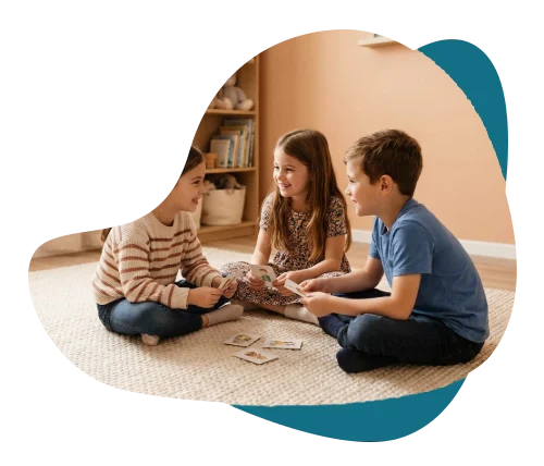 Three children playing a card game together on a playroom rug, representing group therapy for kids in Richmond Hill.